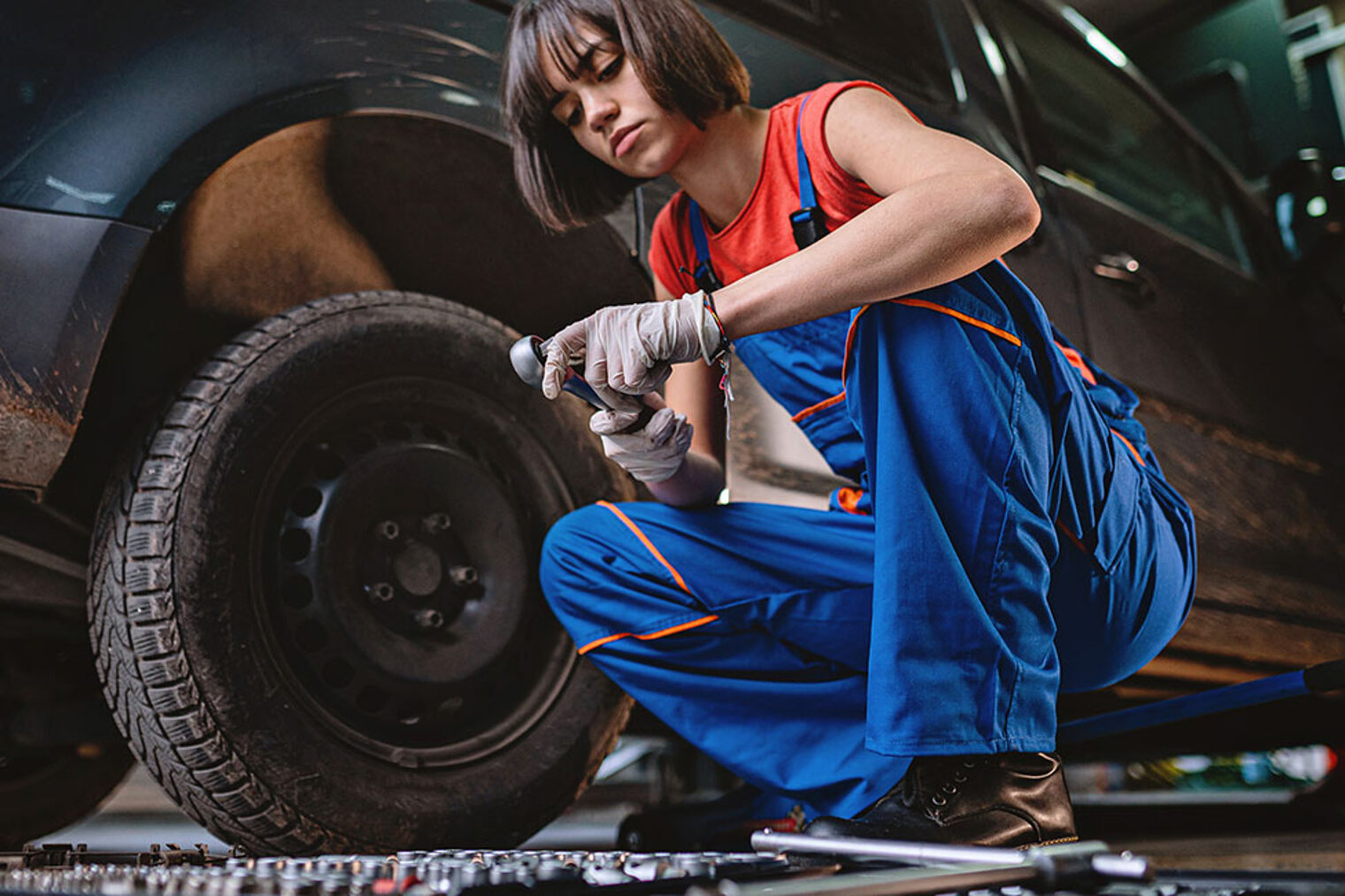 Ausbildung 2025: Werbung für berufliche Bildung und Frauen im Handwerk Automechanikerin wechselt in ihrer Reparaturwerkstatt einen Reifen an einem Auto