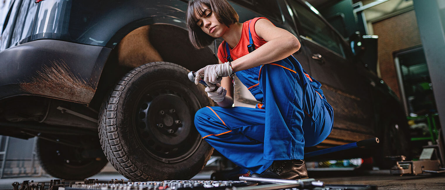 Ausbildung 2025: Werbung für berufliche Bildung und Frauen im Handwerk Automechanikerin wechselt in ihrer Reparaturwerkstatt einen Reifen an einem Auto